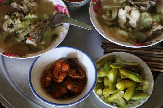 Lunch at the farmer's home, a seafood soup with lots of lime, chewy sweet and sour fish, and homemade pickles, with rice and tea. (Photo: Eve Troeh)
